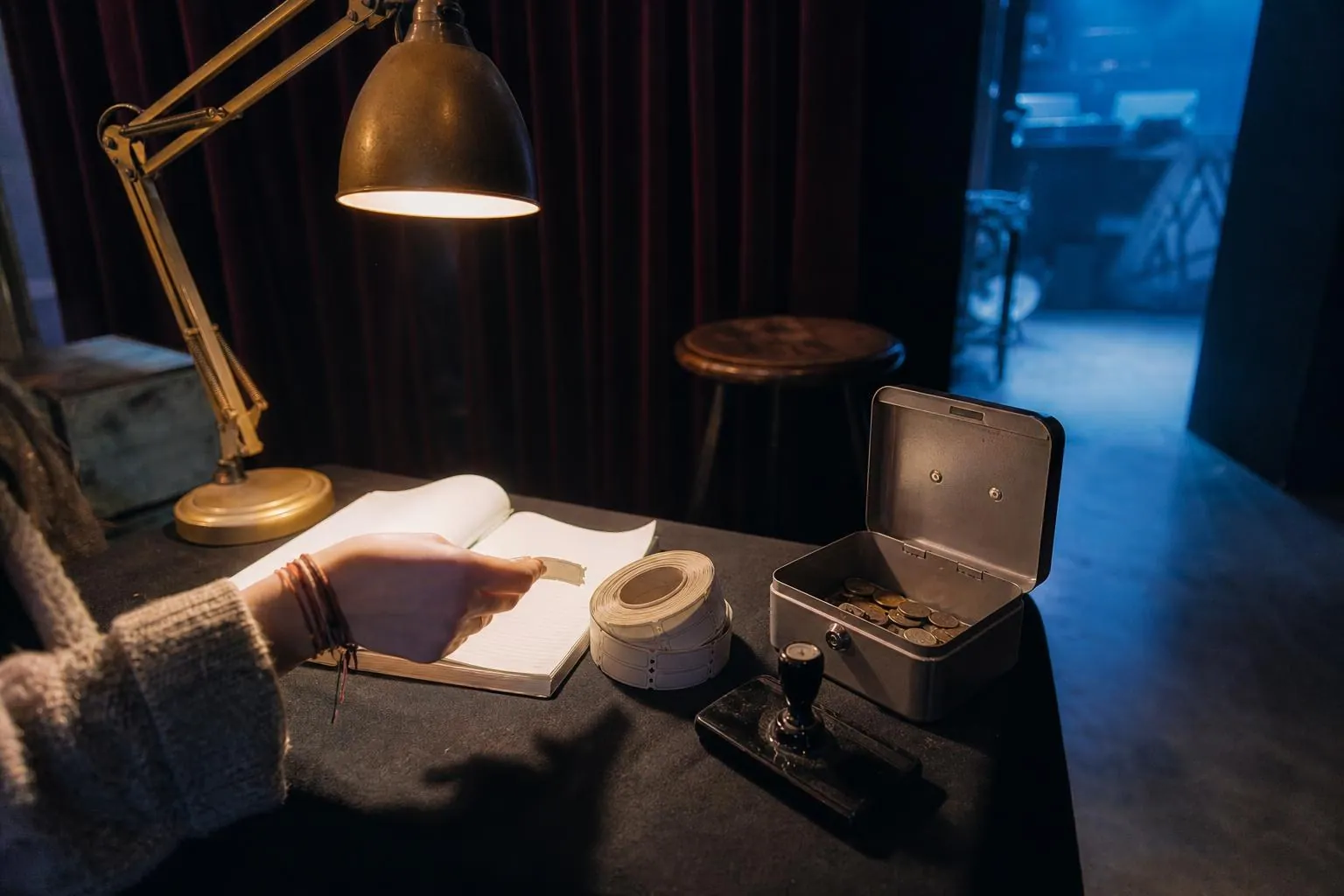 Table d accueil a l entree d une petite salle avec carnet a souches, caisse metallique et main dechirant un ticket